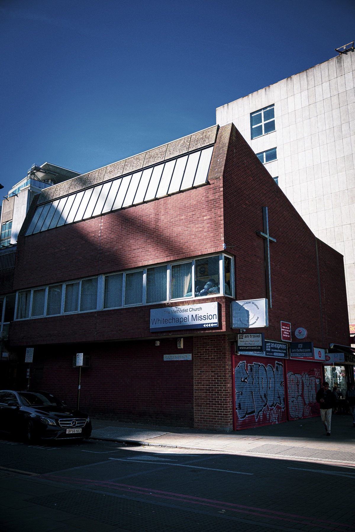 212 Whitechapel Road, plain red brick, two storeys with a sharp double-pitched clerestory roof and a small steel cross fixed to the eastern wall.