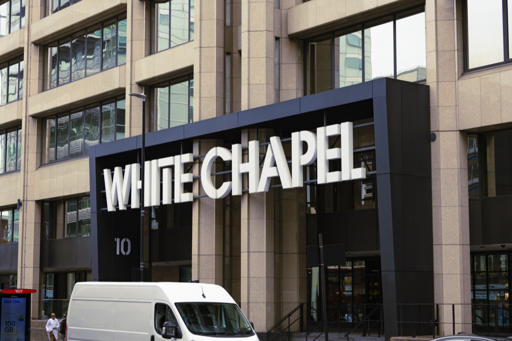 A black ‘Whitechapel’ sign on a glazed building façade, a few doors west of no. 212.